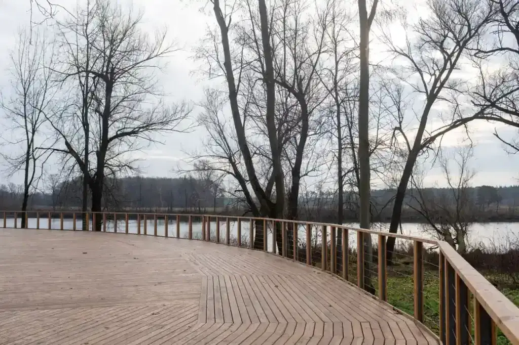 A serene wooden terrace with bare trees overlooking a calm lake during winter in Arkhangel'skoe, Russia.