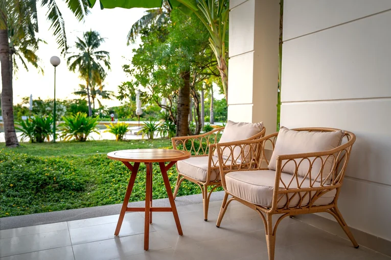A serene patio setup with rattan chairs overlooking a lush tropical garden, perfect for relaxation.