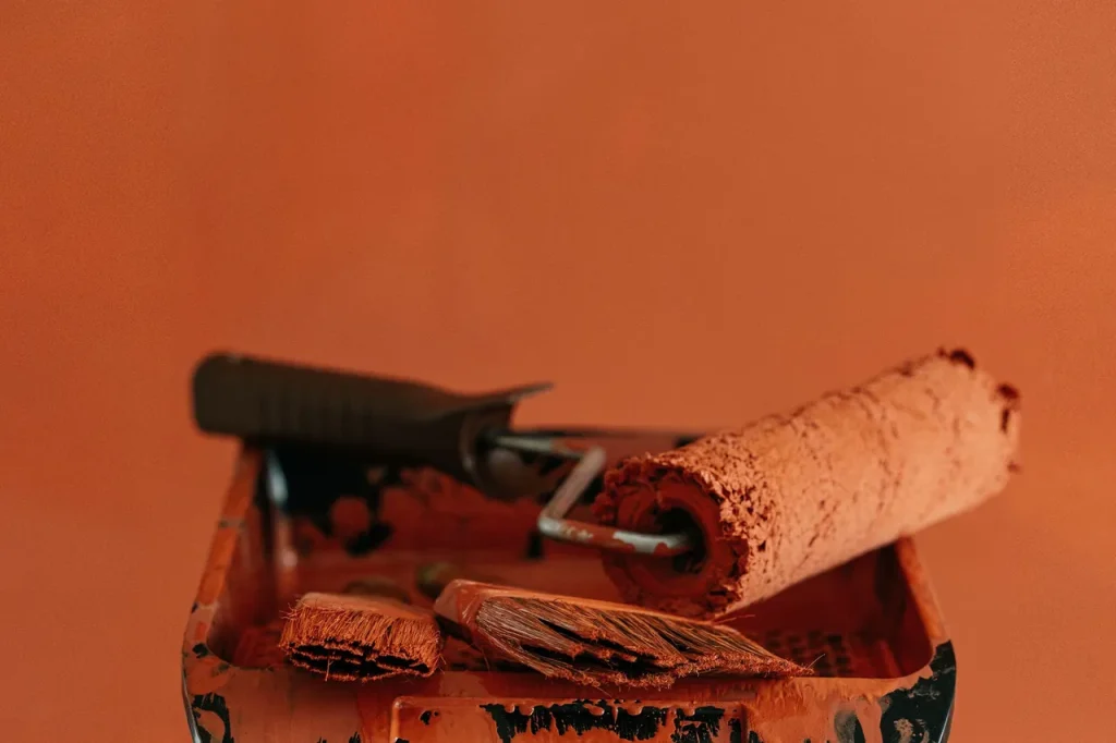 A stepladder holds paint tools for a vibrant orange home renovation project.